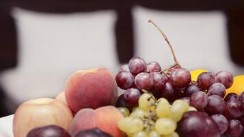 Un frutero con melocotones, uvas y una naranja.