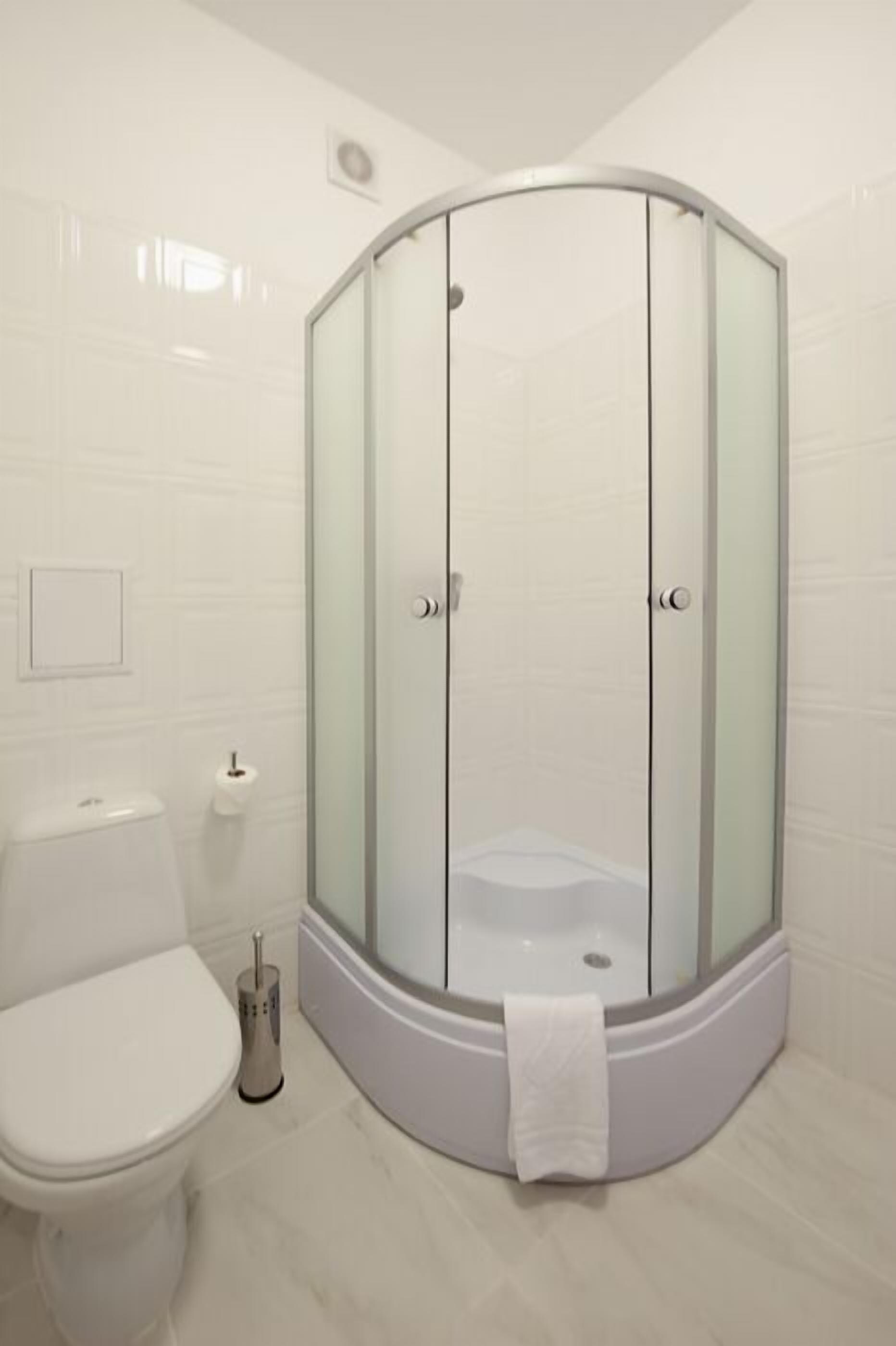 A modern bathroom with a glass-enclosed shower, a toilet, and a sink.