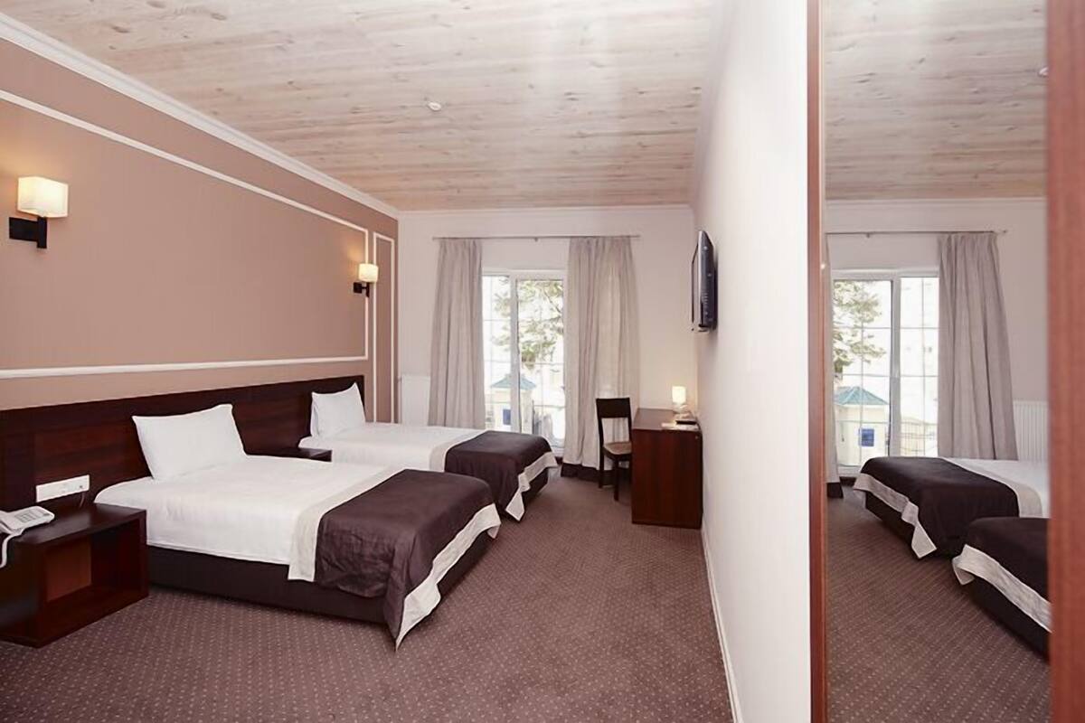 Ein Hotelzimmer mit zwei Betten, einem Schreibtisch, einem Stuhl und einem Fernseher.
