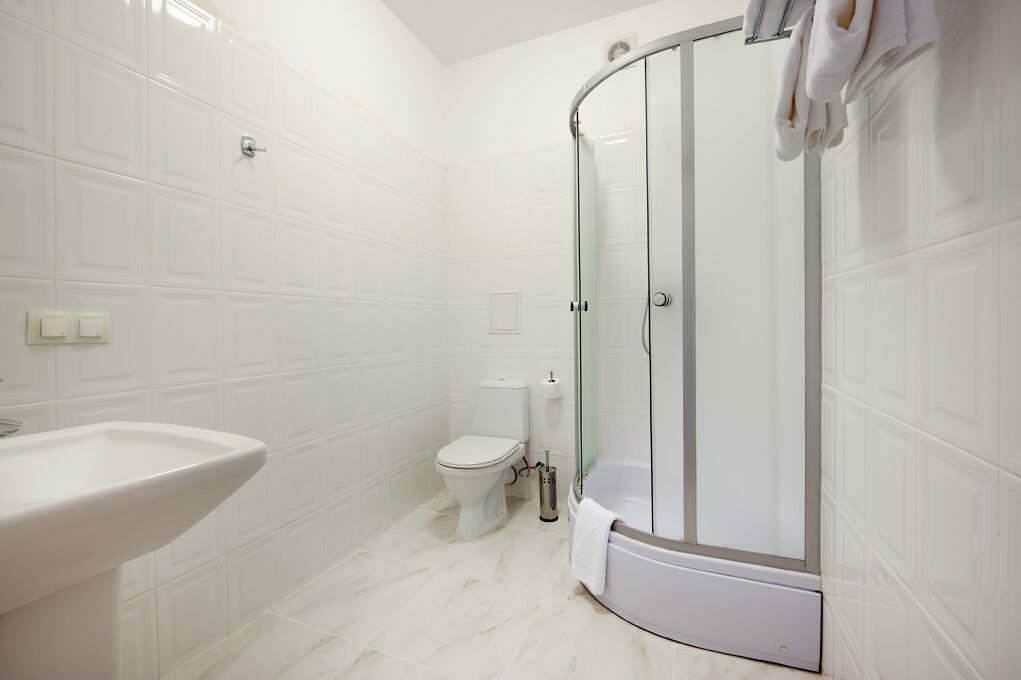Un baño moderno con ducha de vidrio, lavamanos blanco y retrete.
