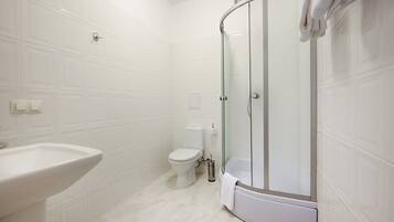 Un baño moderno con ducha de vidrio, lavamanos blanco y retrete.