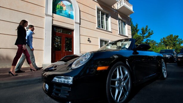 A black convertible parked in front of a building with a sign that reads "GENEVA". - Geneva Resort Hotel (Odesa)