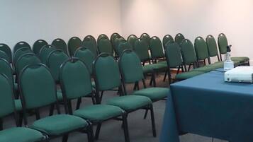 A conference room with rows of green chairs and a table with a projector.