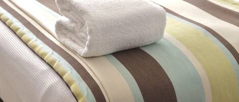 A neatly folded white towel on a striped bedspread.