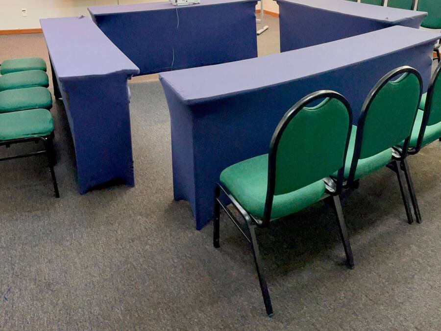 A conference room with a blue table and green chairs.