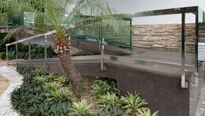 Een moderne binnentuin met een palmboom, verschillende groene planten en een stenen muur.