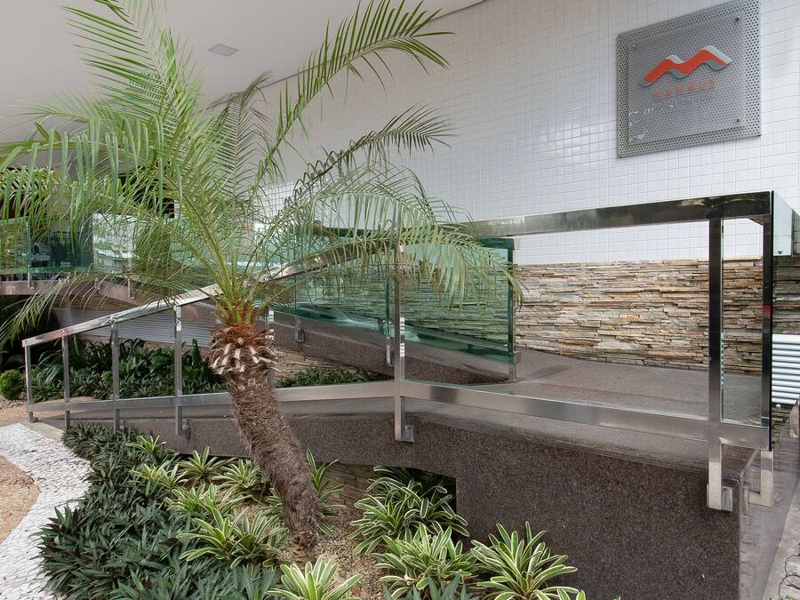 A modern indoor garden with a palm tree, various green plants, and a stone wall.