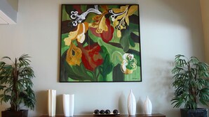 Een hal met twee abstracte schilderijen, een houten bank en potplanten.