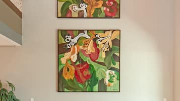 Un interior moderno con dos grandes cuadros florales en la pared, un banco de madera y una planta en maceta.