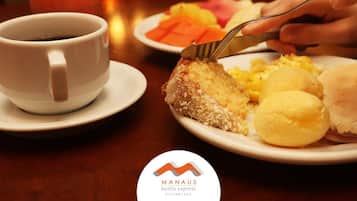 Una mesa de comedor con un plato de comida, una taza de café y un vaso de jugo.