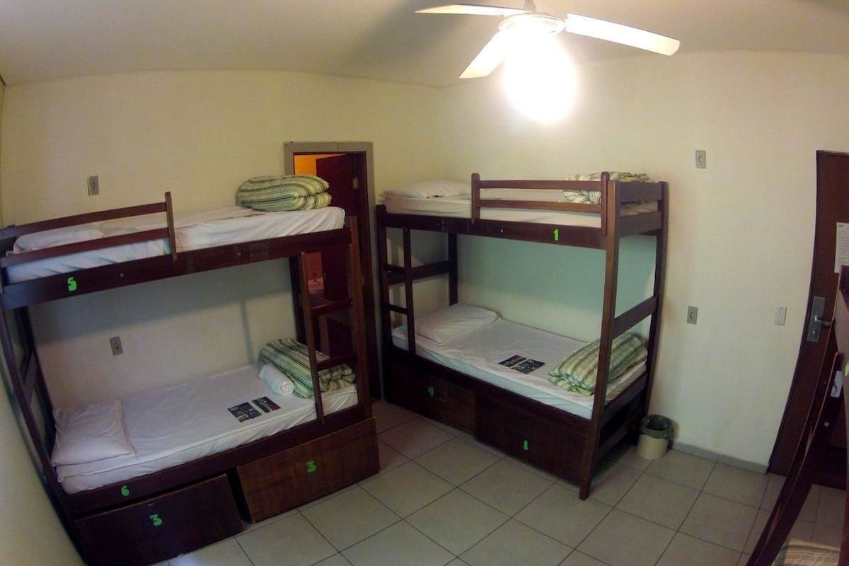 Ein Schlafsaalzimmer mit Etagenbetten, Deckenventilator und Fliesenboden.