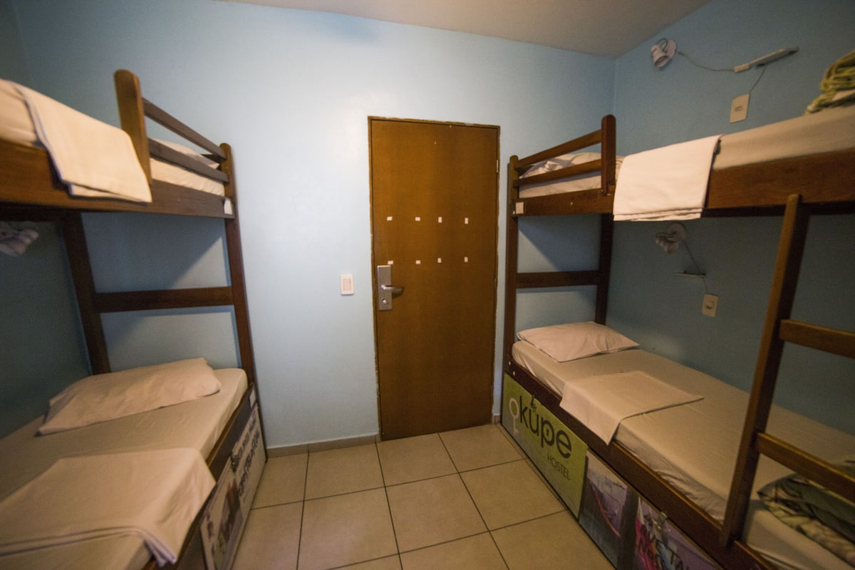 Ein Zimmer mit zwei Etagenbetten, einer Tür und einem Poster an der Wand.