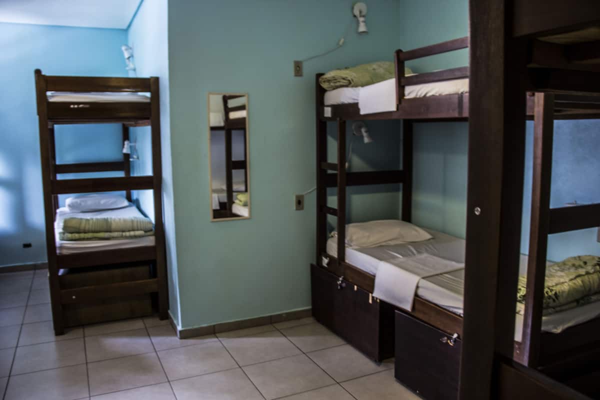 Ein Zimmer mit Etagenbetten, einem Spiegel und einem kleinen Schrank.