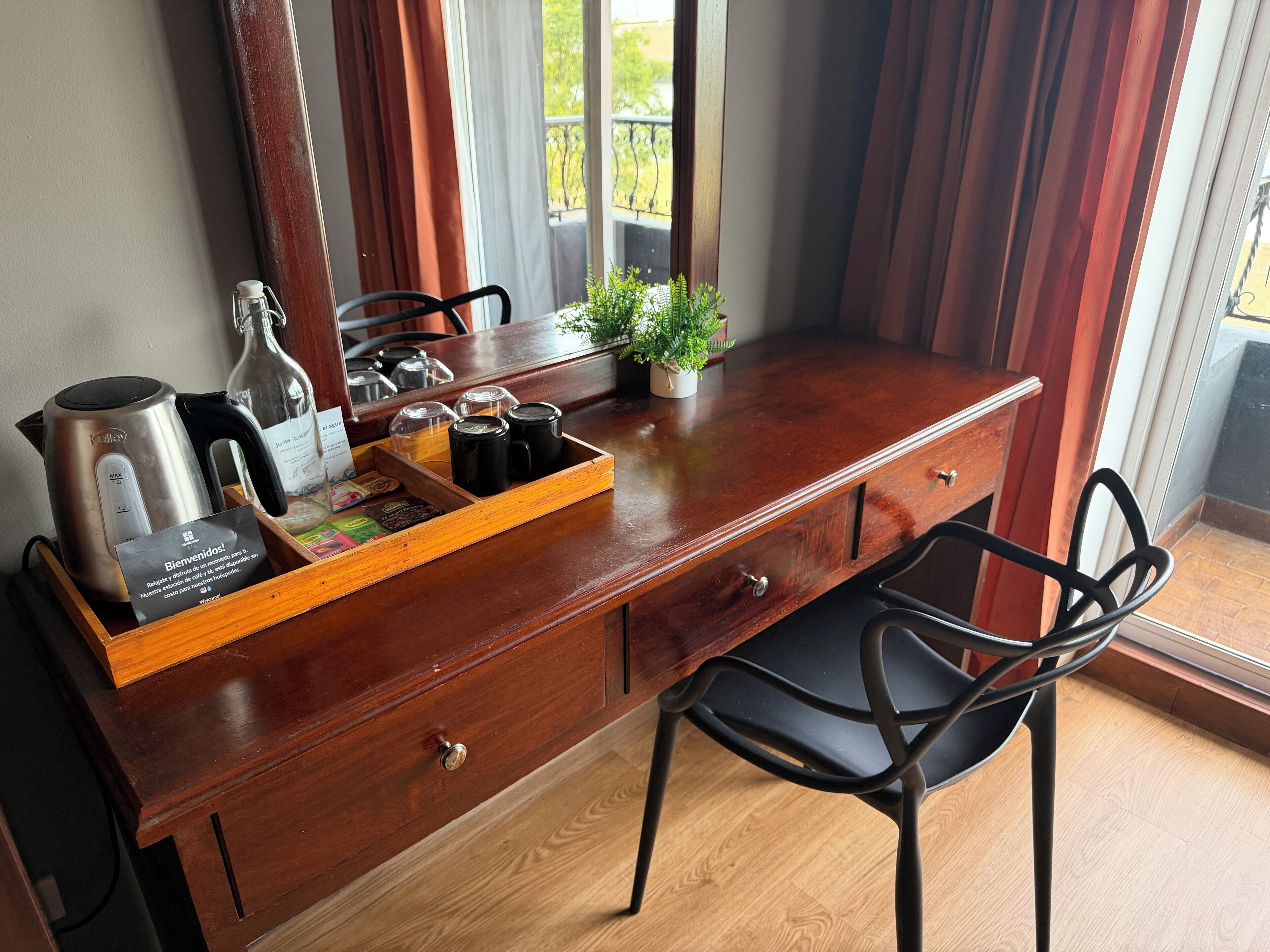 A wooden desk with a kettle, coffee mugs, and a tray with a plant and a menu.