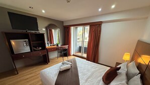 A hotel room with a bed, a desk, a television, and a balcony with curtains. - Blu Inn Hotel (Bogotá)