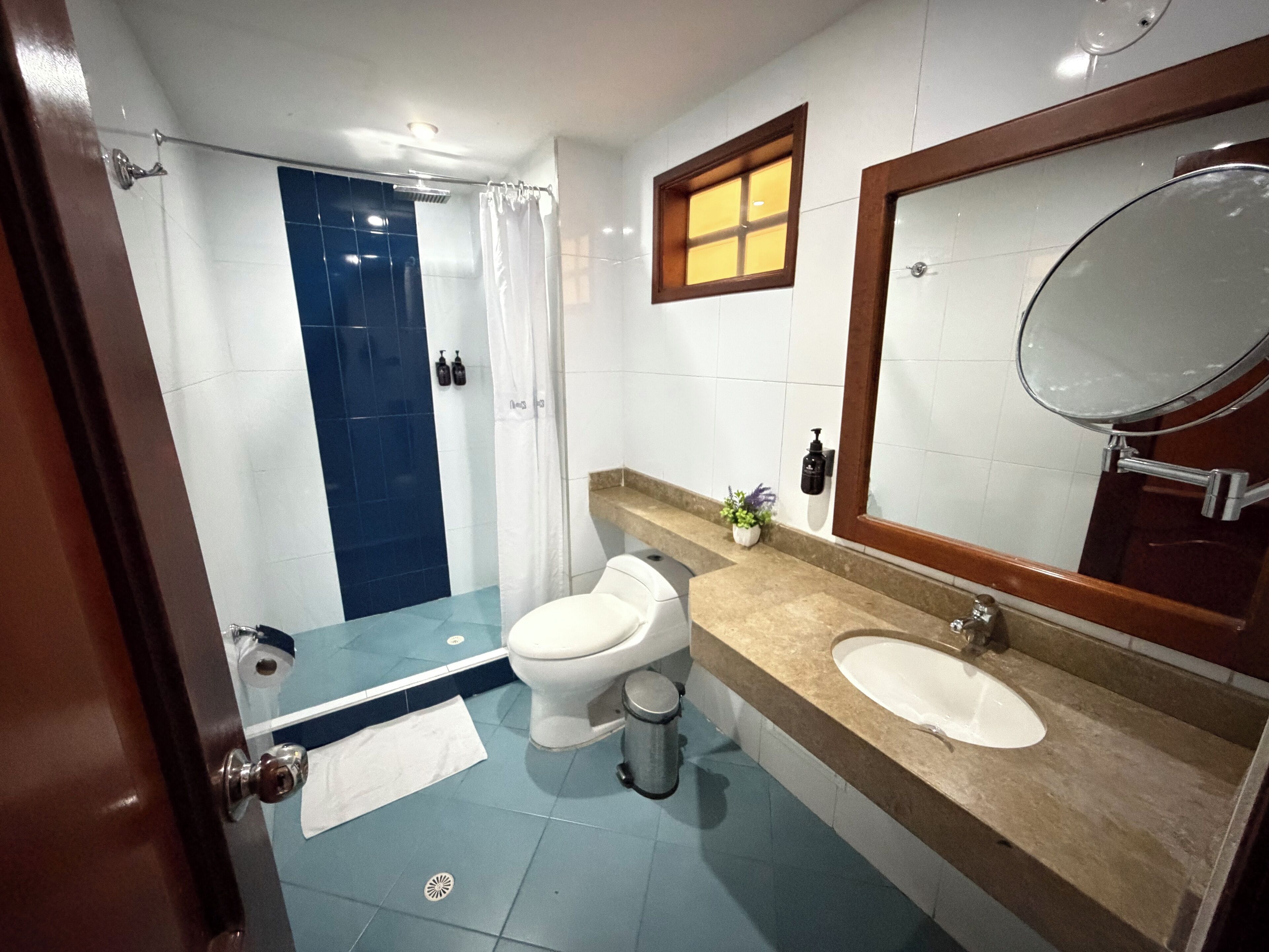 A bathroom with a shower, toilet, sink, and a mirror.