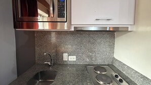 A kitchen with a built-in microwave, a stainless steel sink, and a gas stove. - Blu Inn Hotel (Bogotá)
