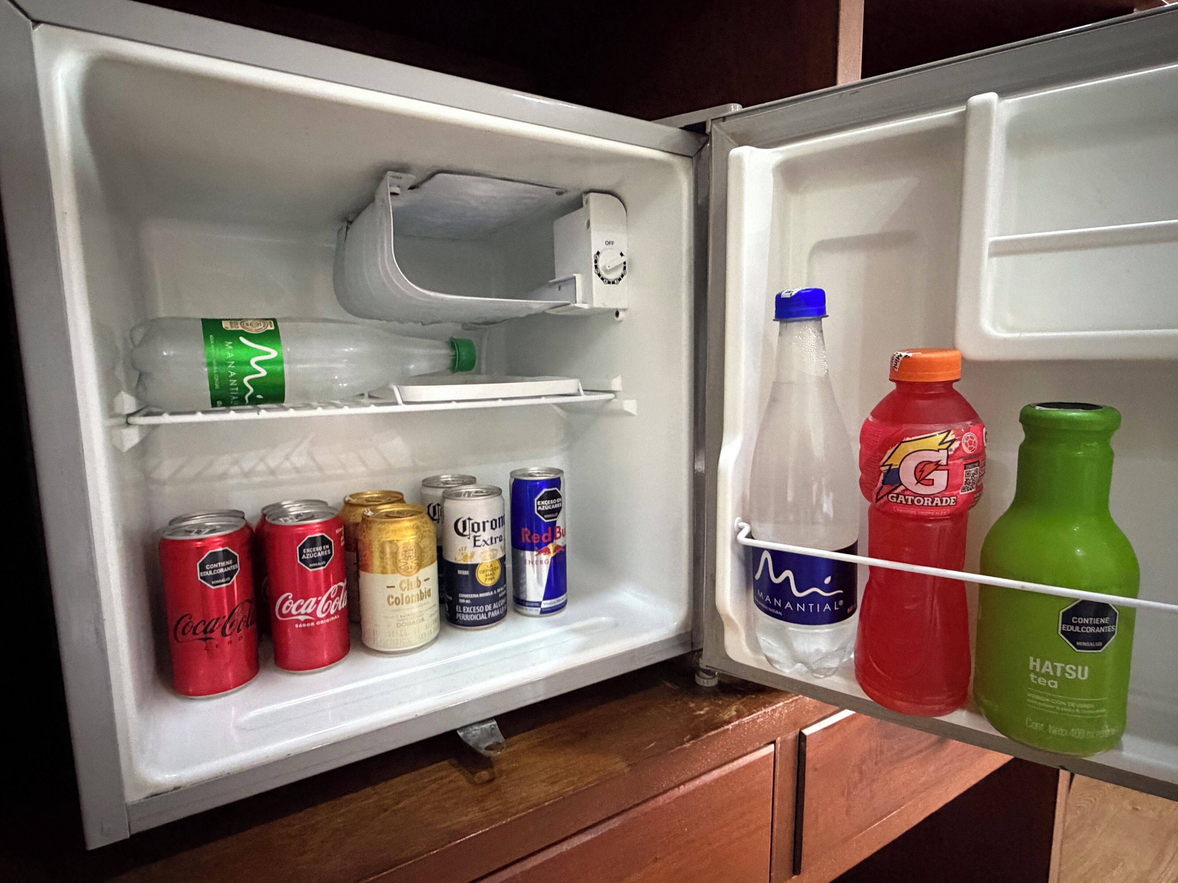 An open refrigerator with beverages and a water bottle.