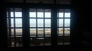 A room with a large window overlooking a beach and a bridge. - Hotel Amsterdam (Mar Del Plata)