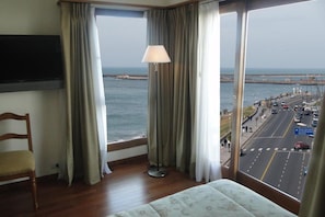 Enjoy a coastal view from the comfort of this room, featuring a large window, a plush bed, and a cozy chair.