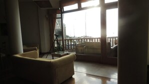 A spacious living room with a large window, a sofa, and a balcony with a railing. - Hotel Amsterdam (Mar Del Plata)