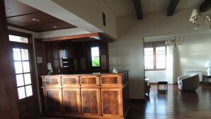 A spacious living area with a wooden bar, large windows, and a chandelier. - Hotel Amsterdam (Mar Del Plata)