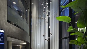 Un vestíbulo moderno con mostrador de recepción, zona de estar e instalación de luces verticales.