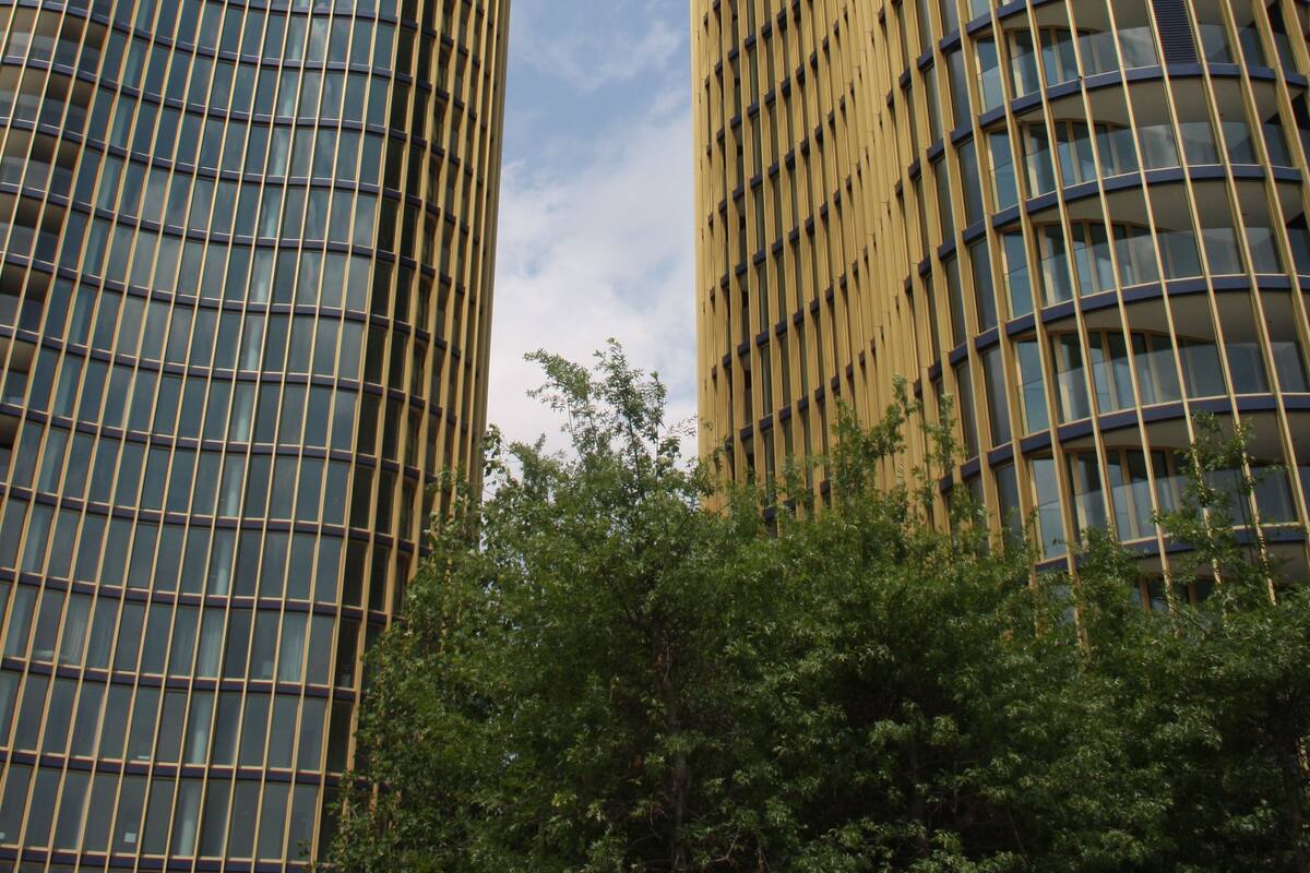 Dos edificios modernos y altos con fachada de entramado y ventanas de vidrio reflectante.