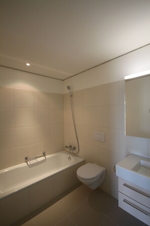 A modern bathroom with a bathtub, toilet, and vanity.