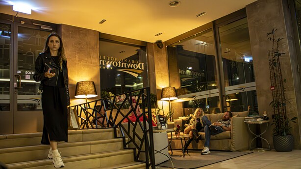 A hotel lobby with a staircase, a sofa, and a potted plant. - Grand Hotel Downtown (Amsterdam)