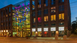 A modern building with a glass facade and a distinctive purple sculpture. - Grand Hotel Downtown (Amsterdam)