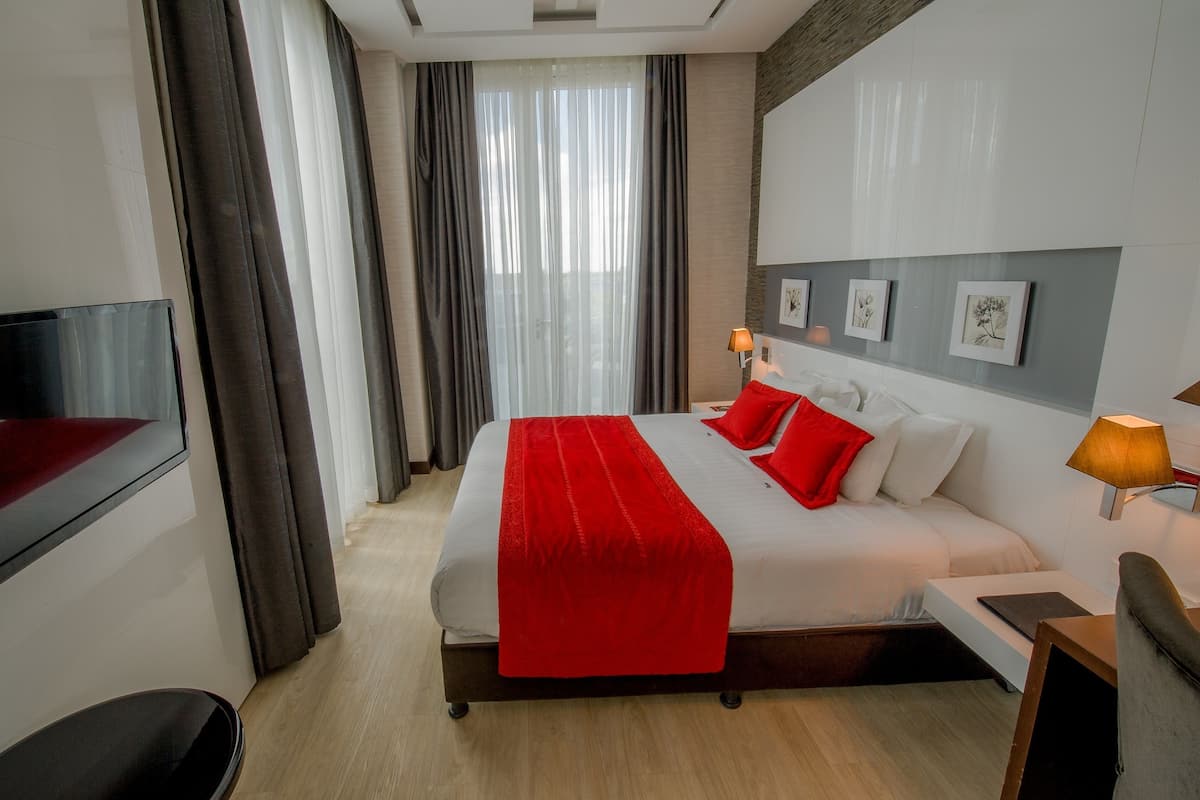 A modern hotel room with a large bed, a flat-screen TV, and artwork on the wall.