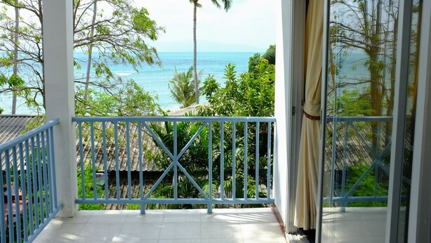 A balcony with a view of the ocean and palm trees. - Thaniza Beachfront Resort (Ko Pha-ngan)