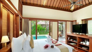 A hotel room with a large bed, a TV, and a view of a swimming pool. - Nyuh Bali Luxury Villas (Seminyak)