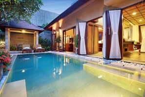 A swimming pool with a clear blue water surface, surrounded by a wooden deck and a covered outdoor seating area. - Nyuh Bali Luxury Villas (Seminyak)