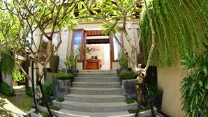 A building with a sign reading "H Bali" at the entrance, surrounded by lush greenery and a stone staircase leading up to the door. - Nyuh Bali Luxury Villas (Seminyak)