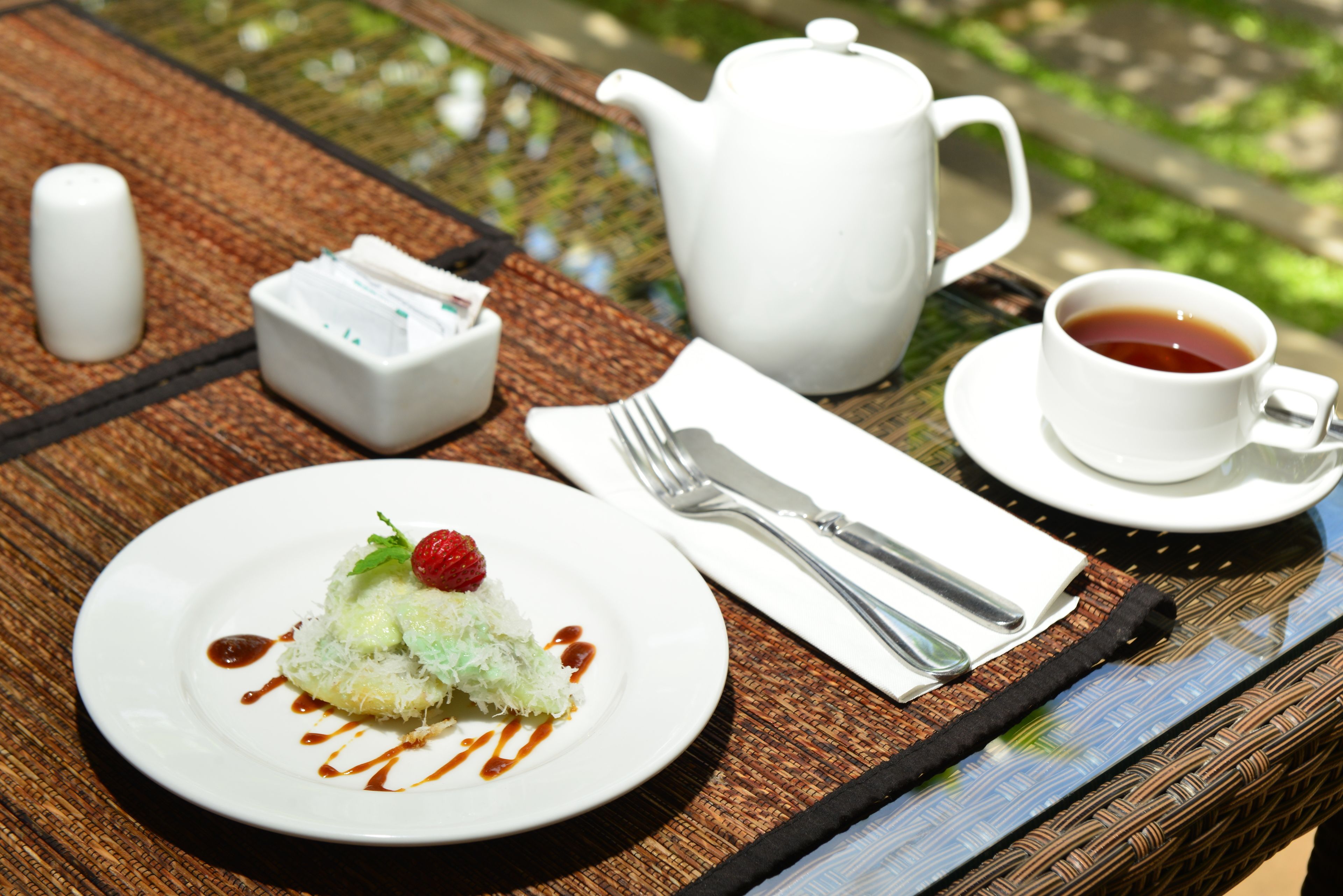 Una mesa dispuesta con un postre, una tetera, una taza de té y un salero.