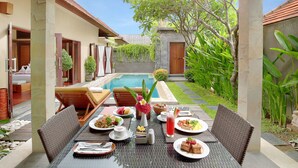 A dining area with a pool view, outdoor seating, and a well-maintained garden. - Nyuh Bali Luxury Villas (Seminyak)