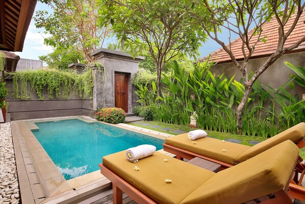 A poolside area with two sun loungers, a small pool, and surrounding greenery. - Nyuh Bali Luxury Villas (Seminyak)