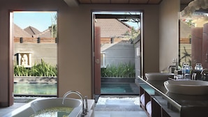 A modern bathroom with a large bathtub, two sinks, and a view of a pool and garden. - Nyuh Bali Luxury Villas (Seminyak)