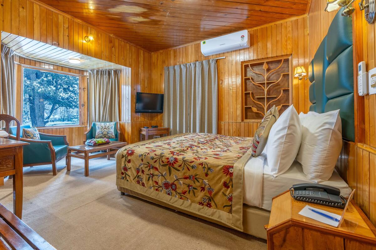Una habitación de madera con una cama, un televisor, un escritorio y una silla.