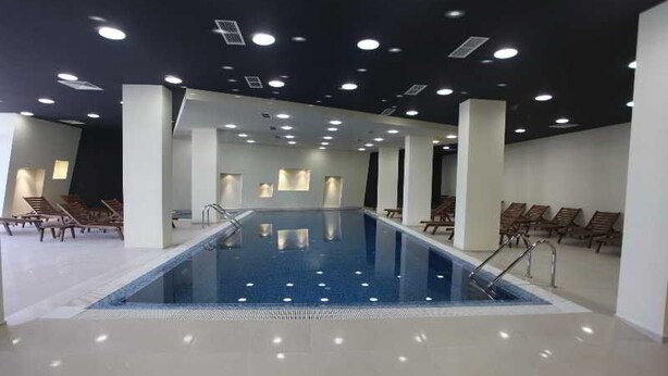 A large indoor swimming pool with multiple lanes, surrounded by lounge chairs and a ceiling with recessed lighting. - Aspen Resort Golf, Ski & Spa (Razlog)