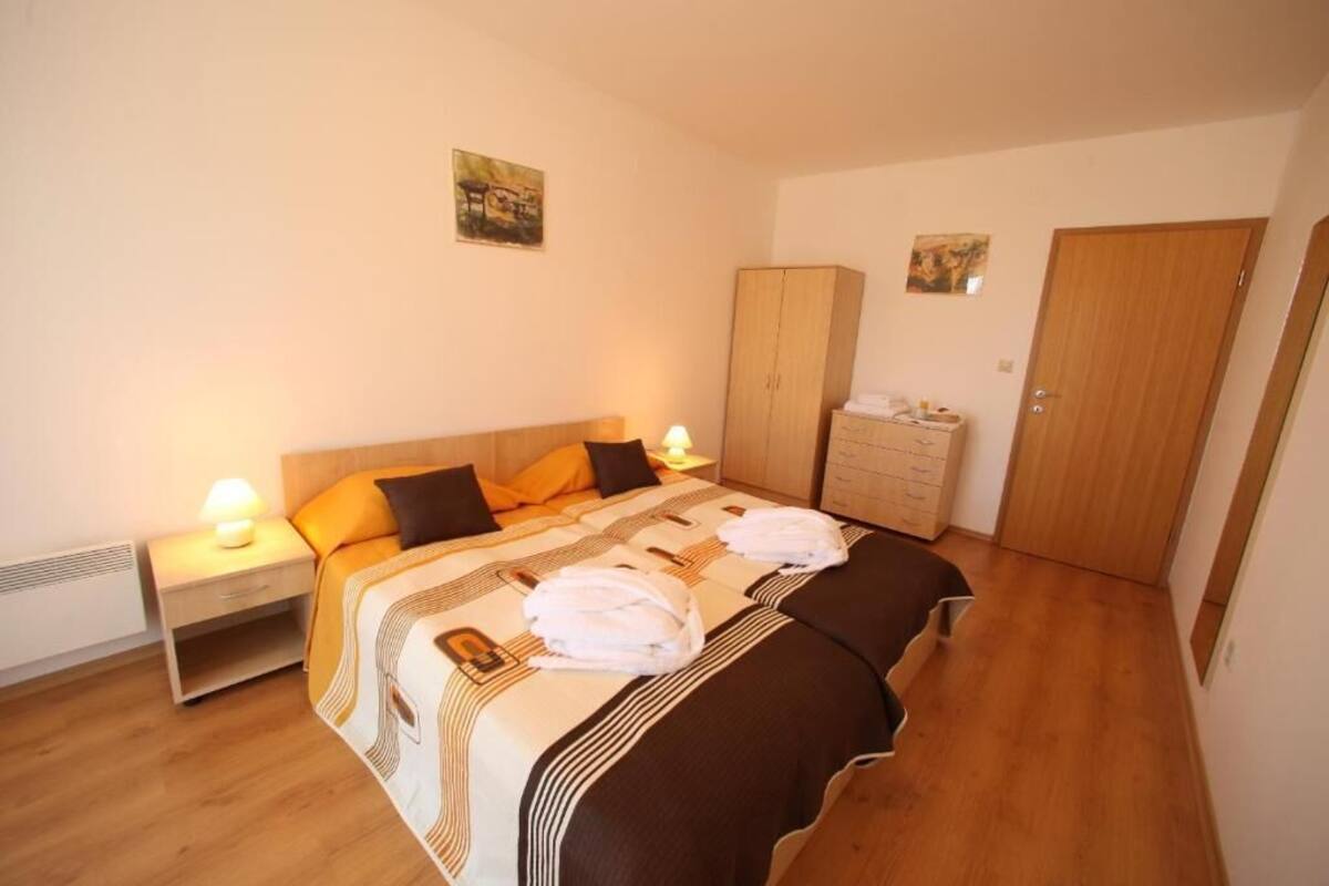 A bedroom with a bed, nightstands, a wardrobe, and a door.