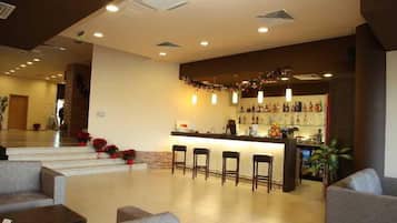 Un hall de hotel con zona de bar, asientos y una escalera que lleva a otro nivel.