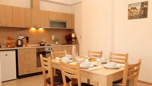 A compact kitchen with wooden cabinets, a dining table set for four, and a small refrigerator. - Aspen Resort Golf, Ski & Spa (Razlog)