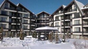 A multi-story hotel with balconies and a covered outdoor seating area. - Aspen Resort Golf, Ski & Spa (Razlog)