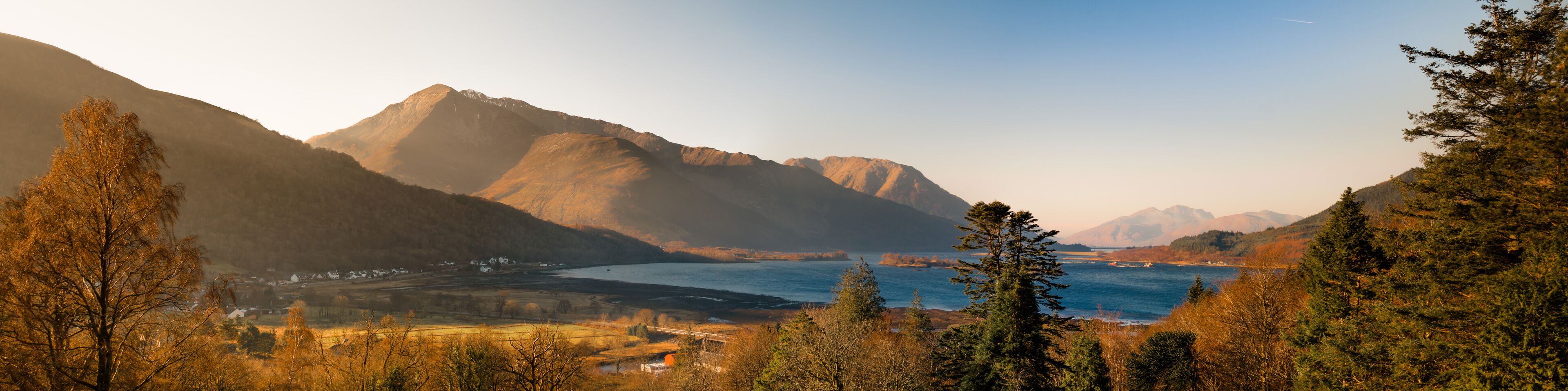 A mountainous landscape with a river and a bridge.