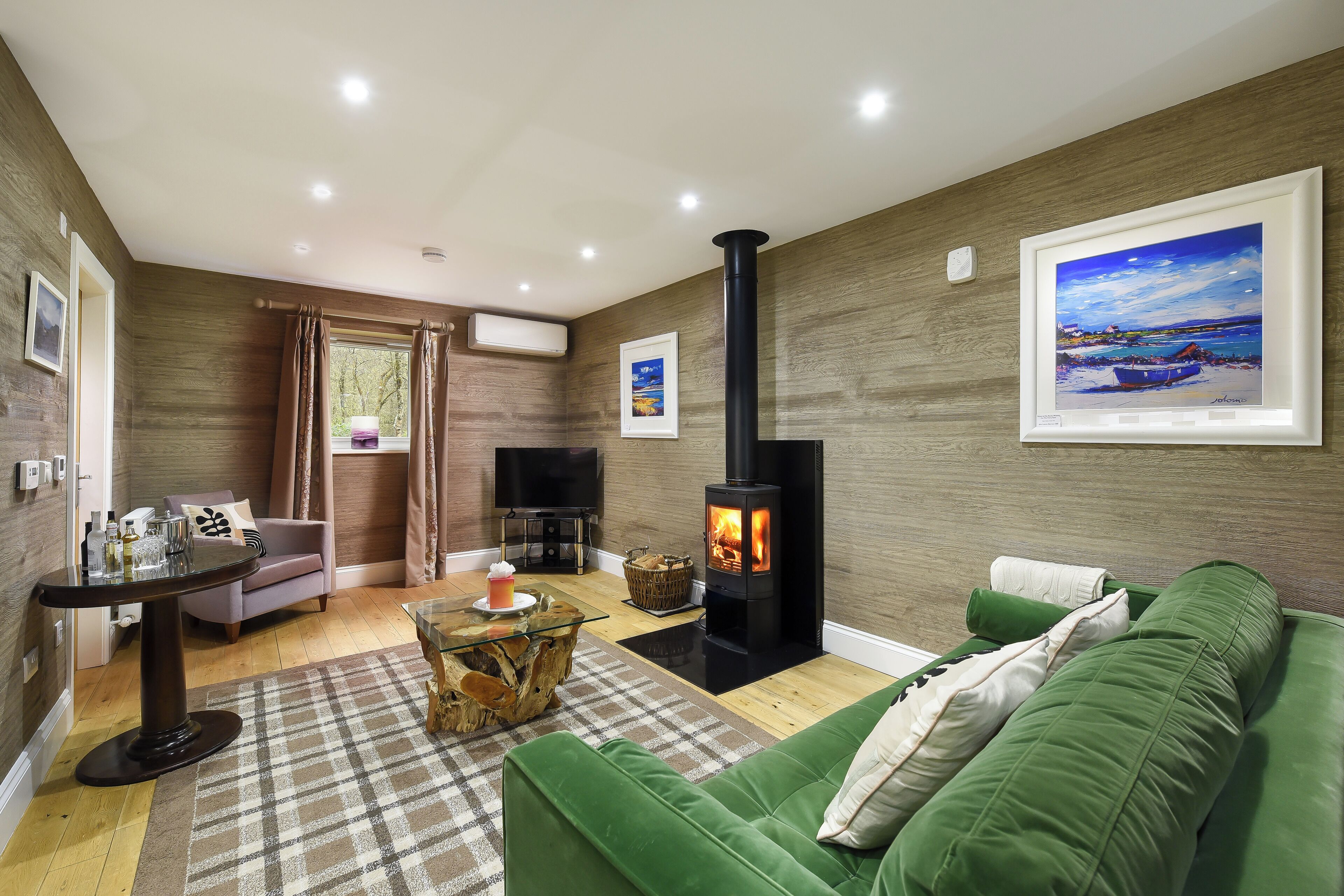 A cozy living room with a green sofa, a coffee table, a fireplace, and a painting on the wall.