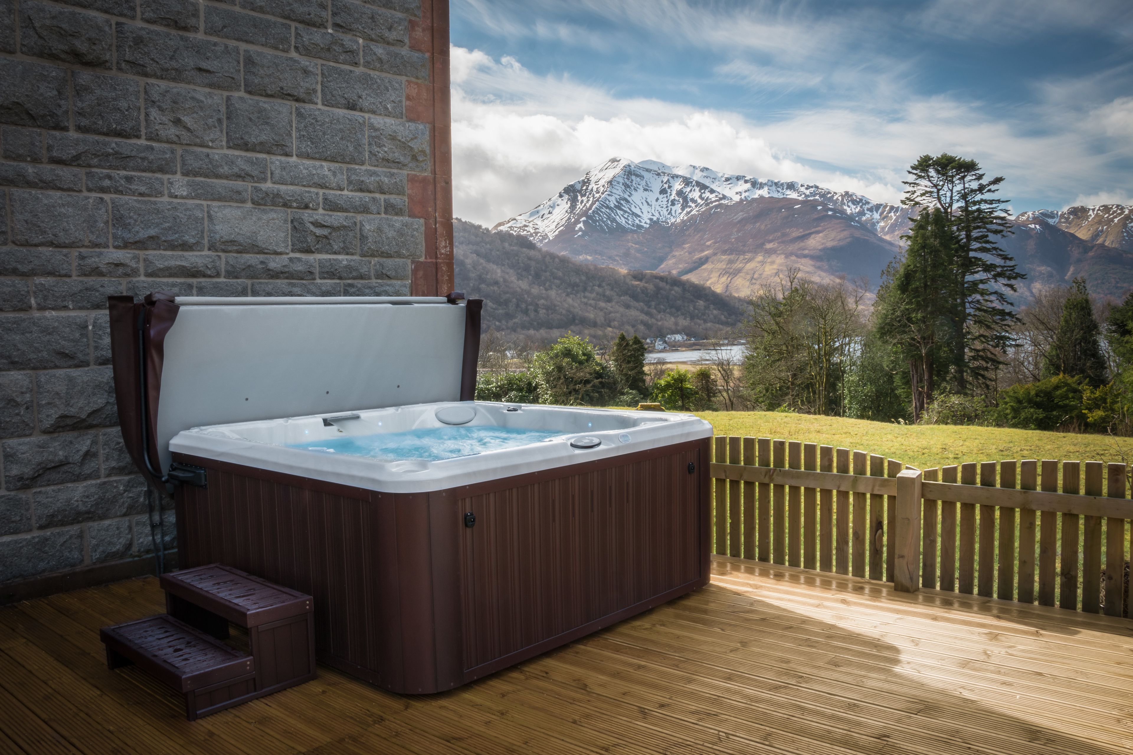 Un bain à remous sur une terrasse en bois avec vue sur les montagnes.