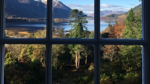 A view through a window with a clear sky, a lake, and mountains in the background.